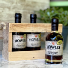 Load image into Gallery viewer, Three bottles of Howles barrel aged syrup crate pack on marble table with plant in background
