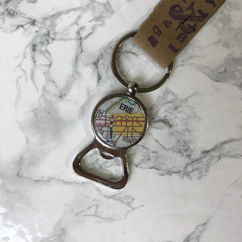 Agatha and Emily Erie map bottle opener keychain on a white marble background