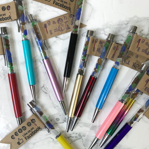 Variety of the Agatha and Emily Erie beach glass pens in different colors on a white marble background