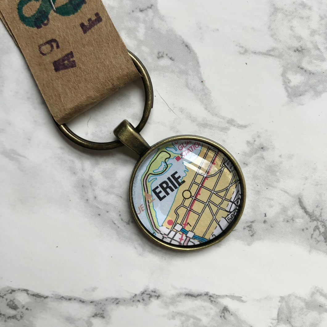 Close up of the Agatha and Emily Erie Map keychain on a white marble background