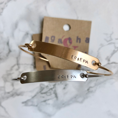 Agatha and Emily Erie PA silver and gold metal bracelets on a white marble background